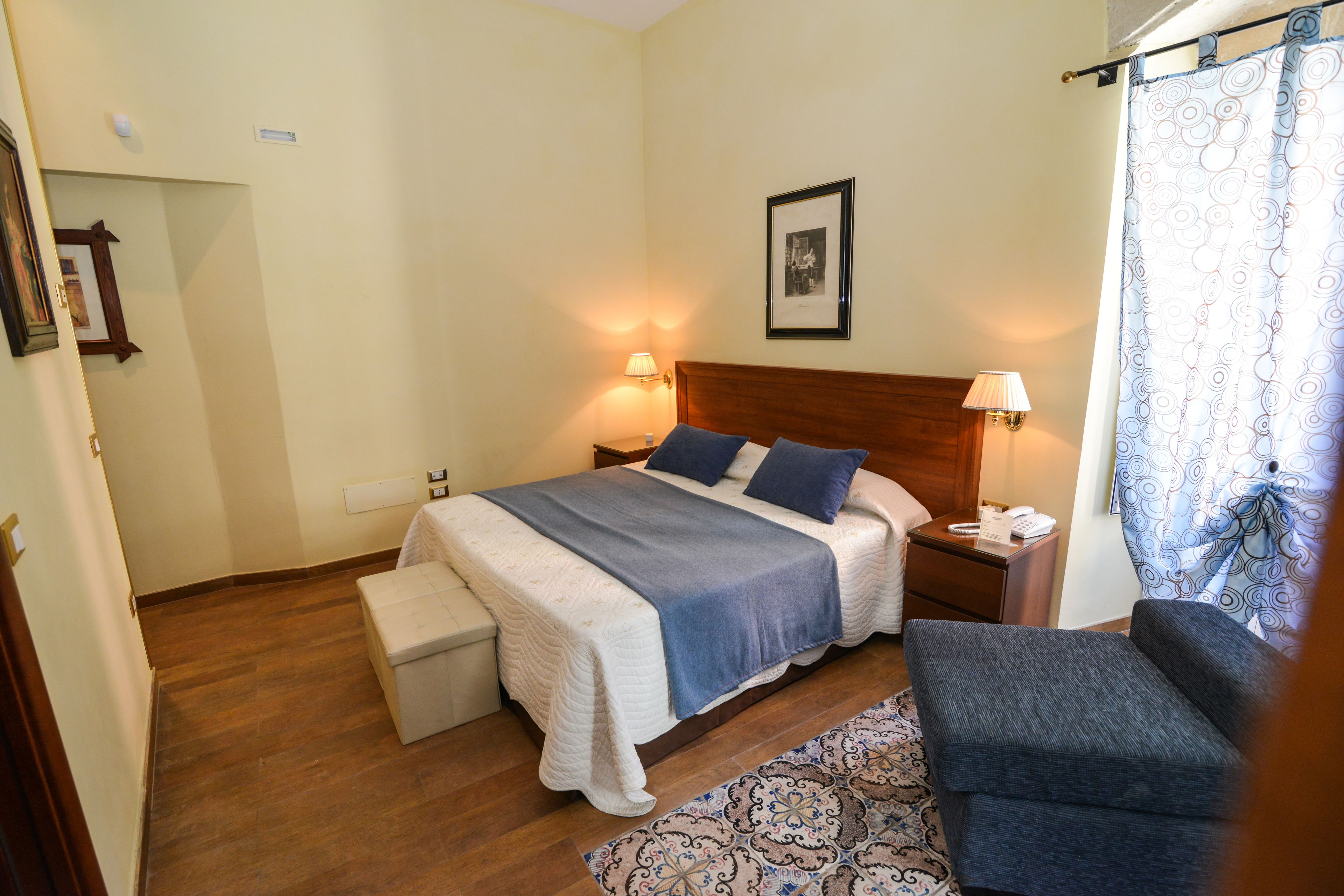 A neatly arranged bedroom with a bed, bedside tables, a chair, and a small table.