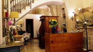 A spacious room with a wooden cabinet, a staircase, and a stone wall. - San Andrea Degli Armeni B&B di Charme - Dimora Storica (Taranto)