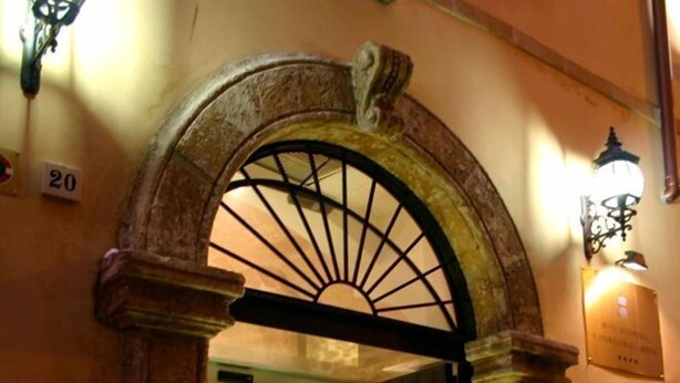 A stone archway entrance to a building with a number '20' sign above it, a door, and a wall-mounted light fixture. - San Andrea Degli Armeni B&B di Charme - Dimora Storica (Taranto)