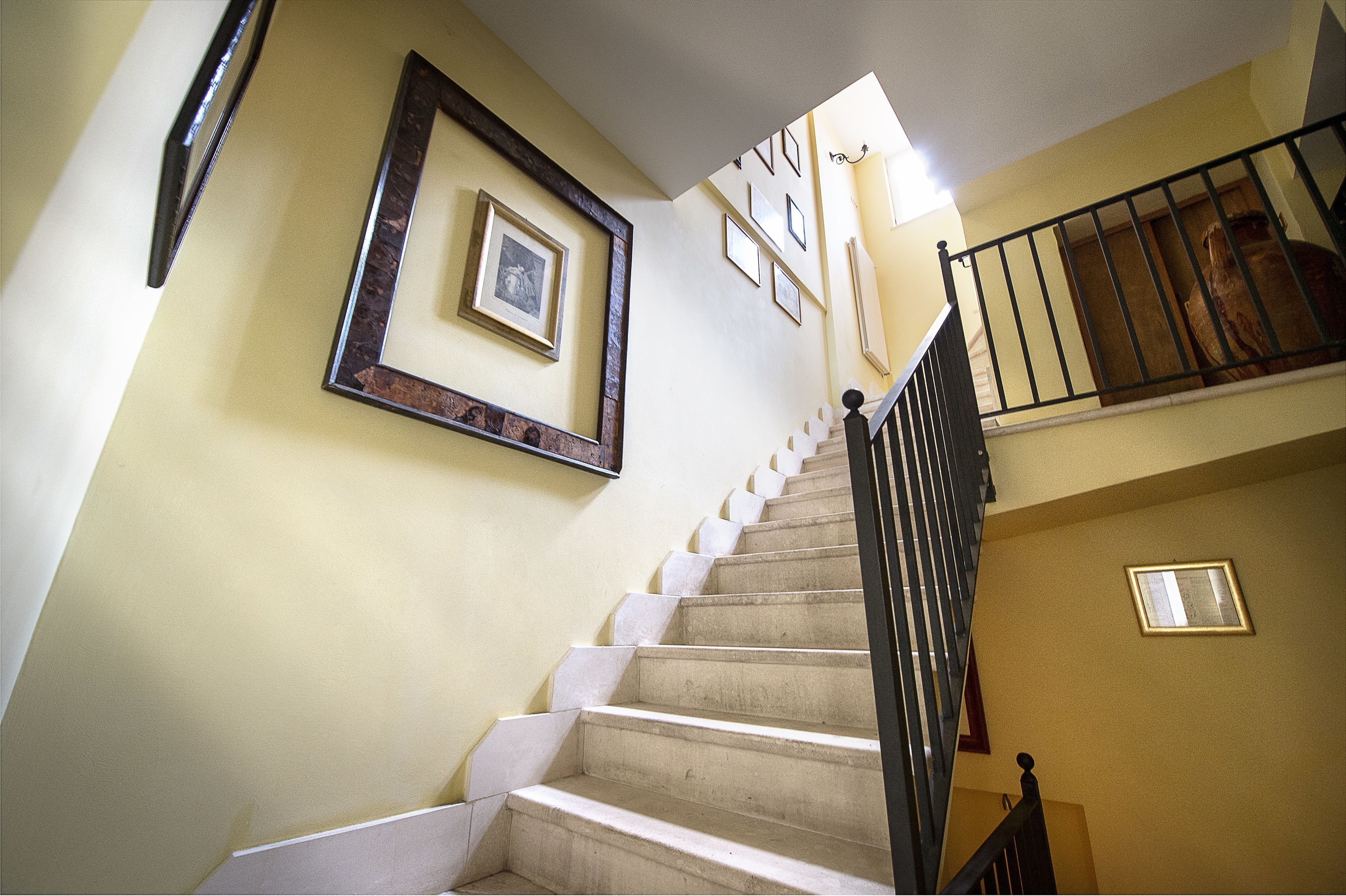 A staircase with a handrail, a light fixture, and framed pictures on the wall.