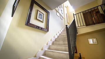 A staircase with a handrail, a light fixture, and framed pictures on the wall.