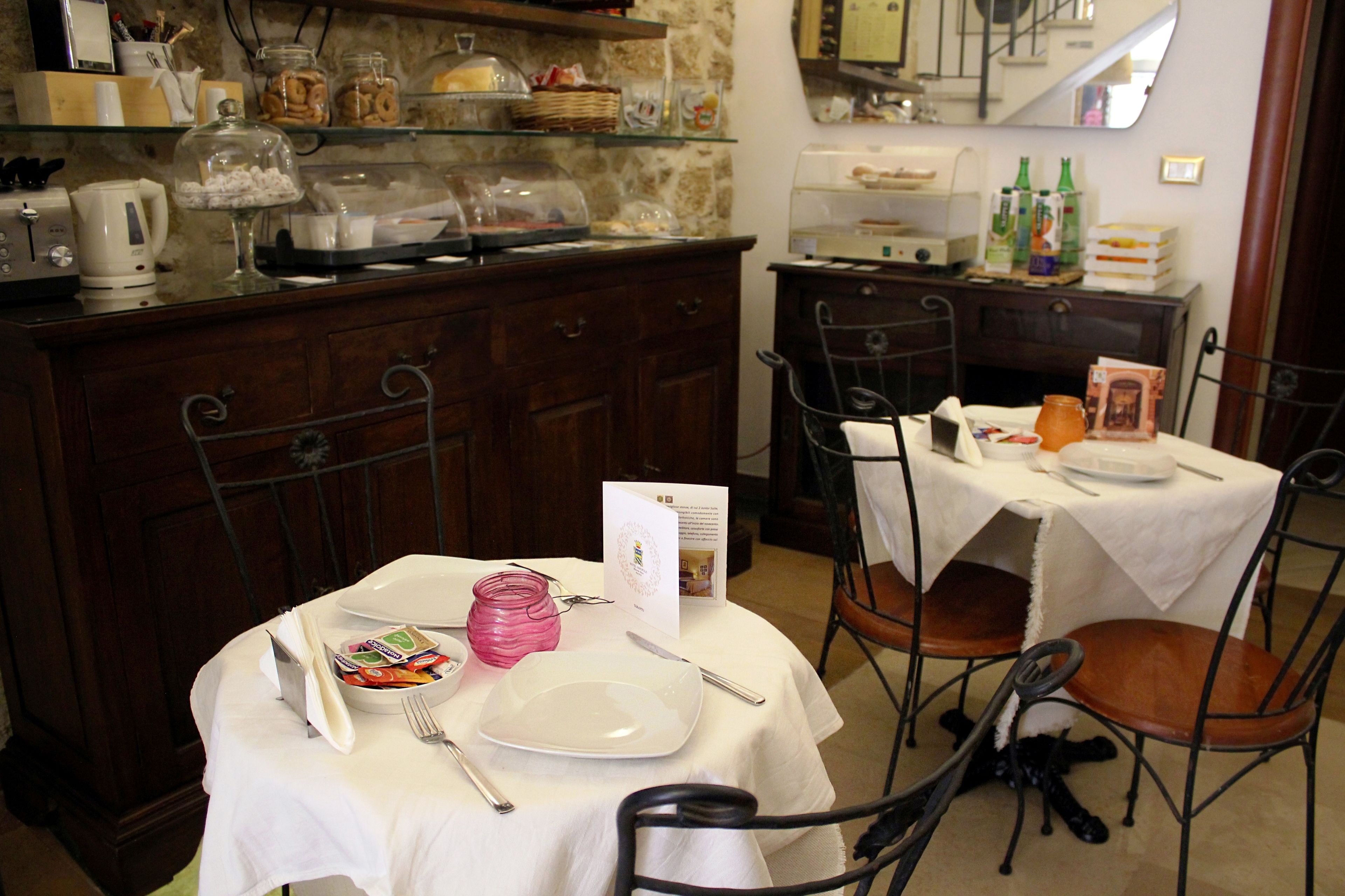 Un comedor con una mesa dispuesta para dos, una cafetera y una barra con distintos alimentos.