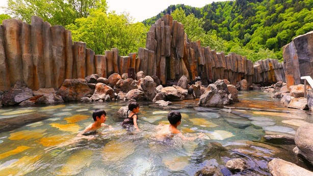 A natural hot spring with clear water, surrounded by large rocks and trees. - Sounkyo Kanko Hotel (Kamikawa)