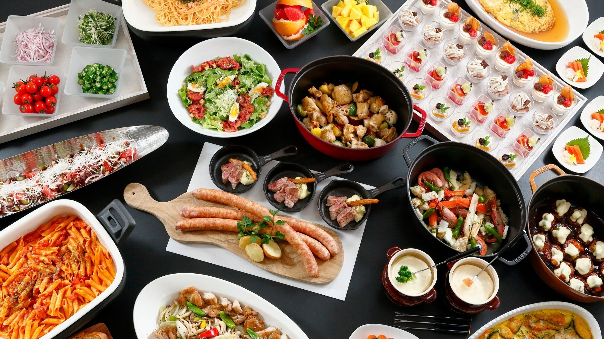 A variety of dishes including pasta, salads, and appetizers spread out on a table.