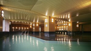 A large indoor swimming pool with multiple lanes, wooden paneling, and built-in lighting fixtures. - Sounkyo Kanko Hotel (Kamikawa)