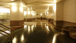 A spacious, well-lit public restroom with multiple sinks, benches, and a tiled floor. - Sounkyo Kanko Hotel (Kamikawa)