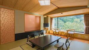 A traditional Japanese-style room with tatami flooring, a low table, and a television. - Sounkyo Kanko Hotel (Kamikawa)