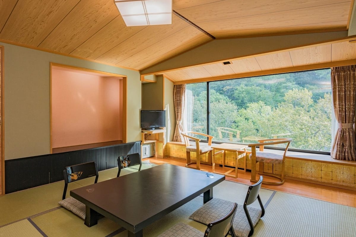 Une pièce de style japonais traditionnel, avec un sol recouvert de tatamis, une table basse et un téléviseur.