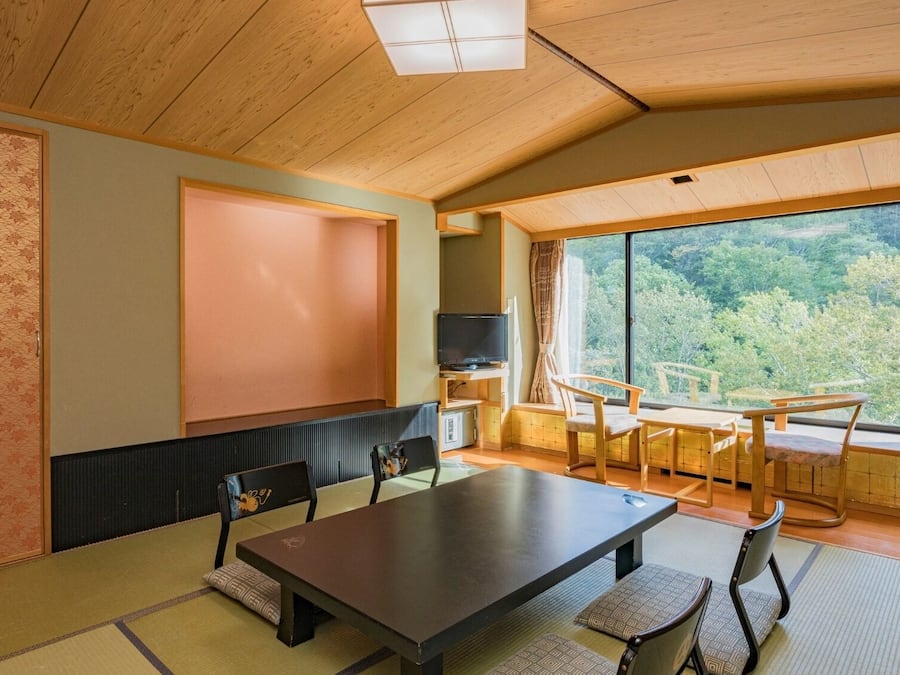 A traditional Japanese-style room with tatami flooring, a low table, and a television.