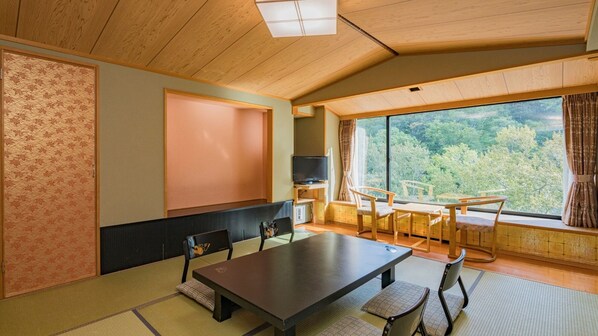 Una habitación tradicional japonesa con suelo de tatami, una mesa baja y un televisor.