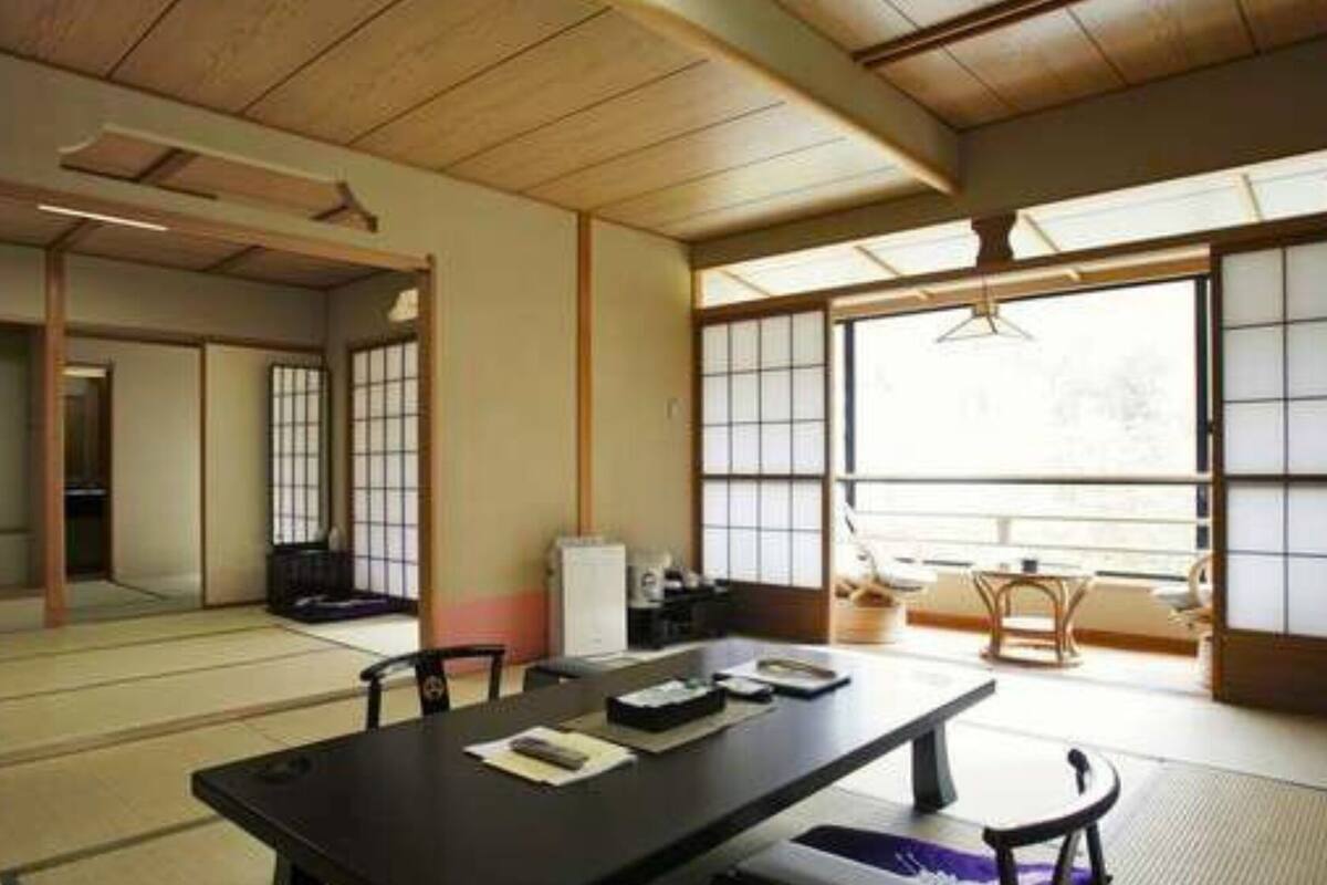 Une pièce de style japonais traditionnel, avec un sol recouvert de tatamis, une table basse avec des coussins et des portes coulissantes en papier de riz (shoji).