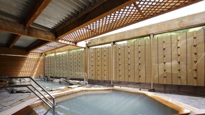 A traditional Japanese onsen with a wooden interior, stone flooring, and a wooden fence. - Sounkyo Kanko Hotel (Kamikawa)