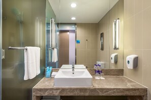 Une salle de bain moderne avec une douche à parois de verre, un lavabo blanc et un miroir.