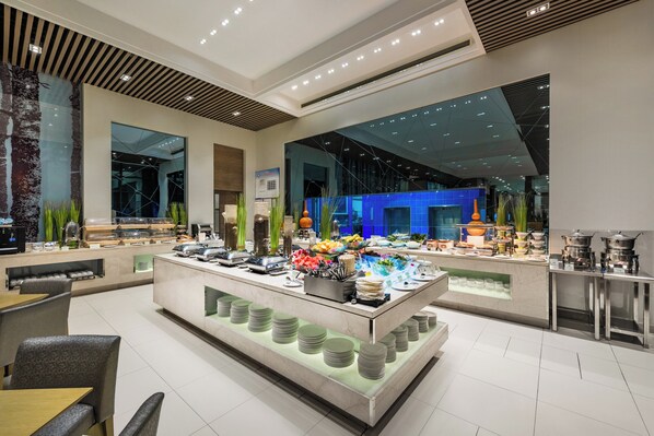 A modern hotel lobby with a central buffet area, seating arrangements, and a large window providing a view of the cityscape. - Holiday Inn Express Beijing Yizhuang by IHG (Beijing)