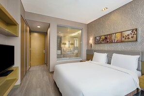 Une chambre d’hôtel avec un grand lit, une télévision, une salle de bain avec un miroir et un élément décoratif mural.