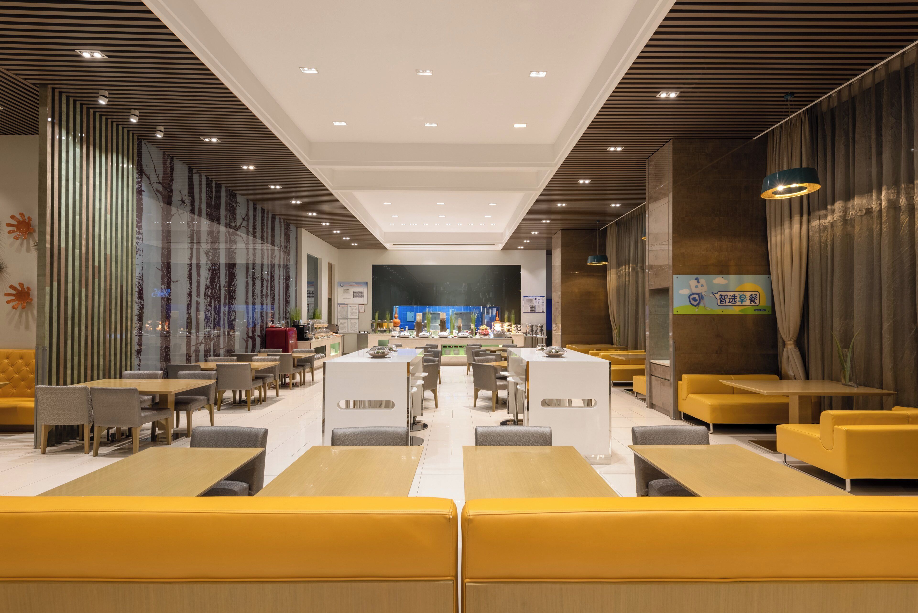 En moderne hotellobby med et centralt receptionstårn, siddepladser og et stort vindue.