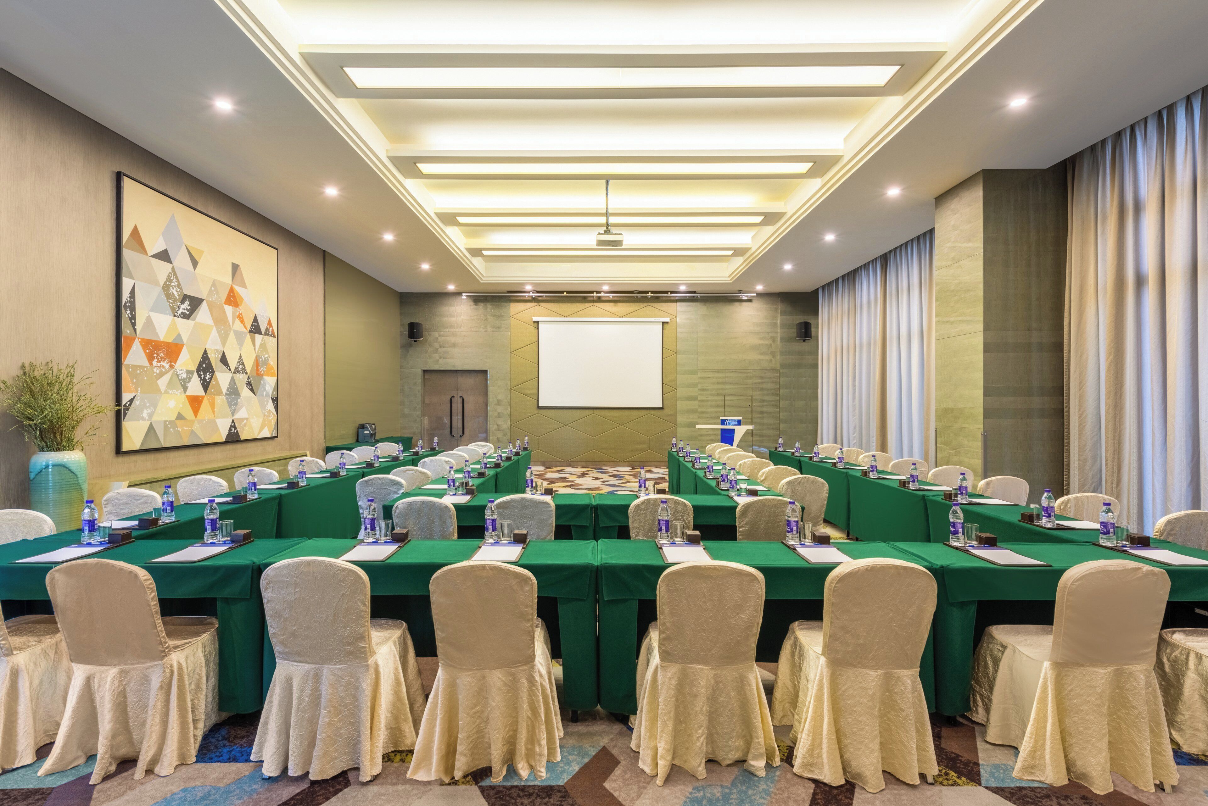 A conference room with a long table, chairs, and a projector screen.