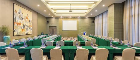 A conference room with a long table, chairs, and a projector screen.
