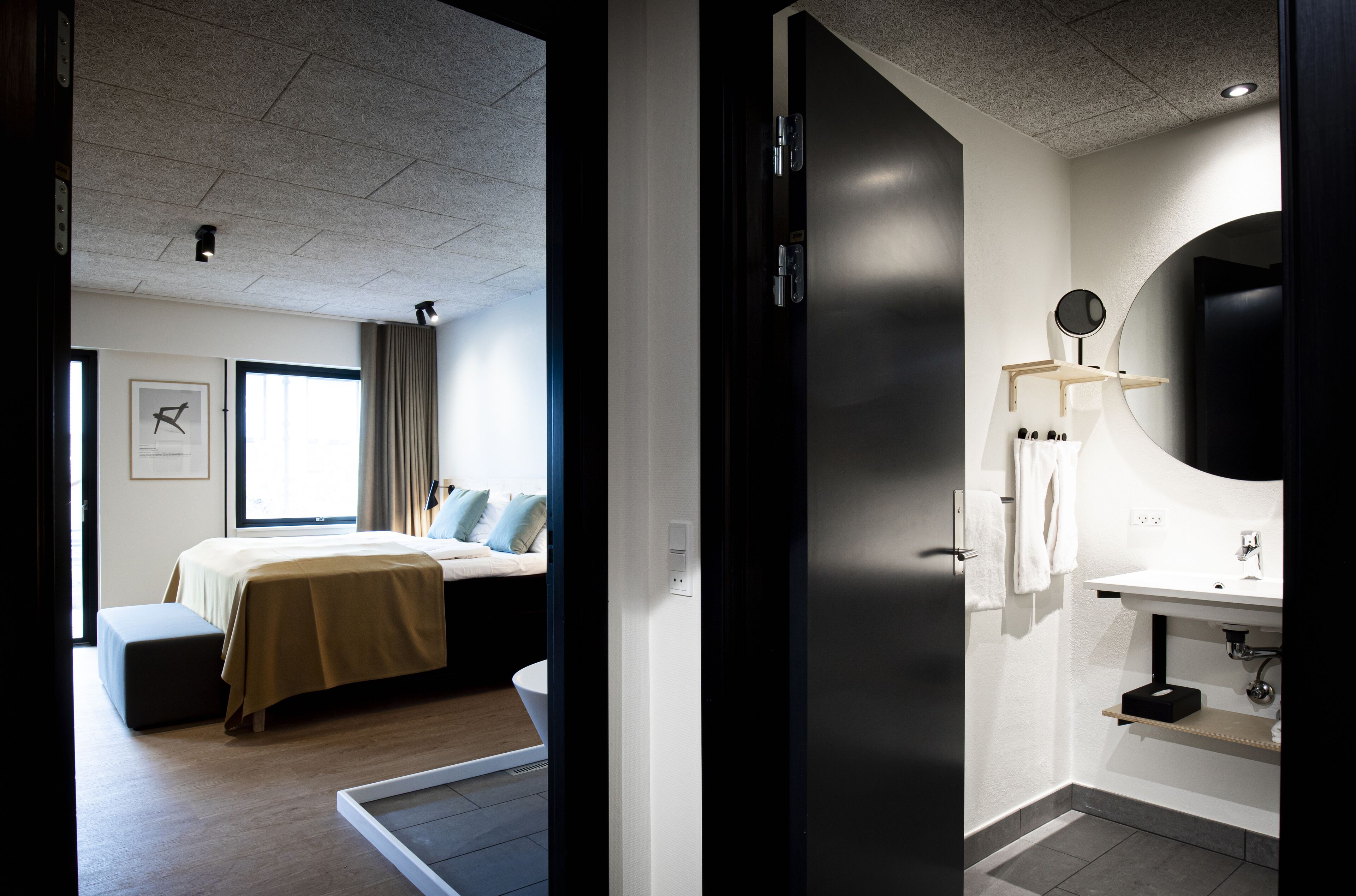 Une chambre d’hôtel comprenant un lit, une table de chevet et une salle de bain avec un lavabo et un miroir.