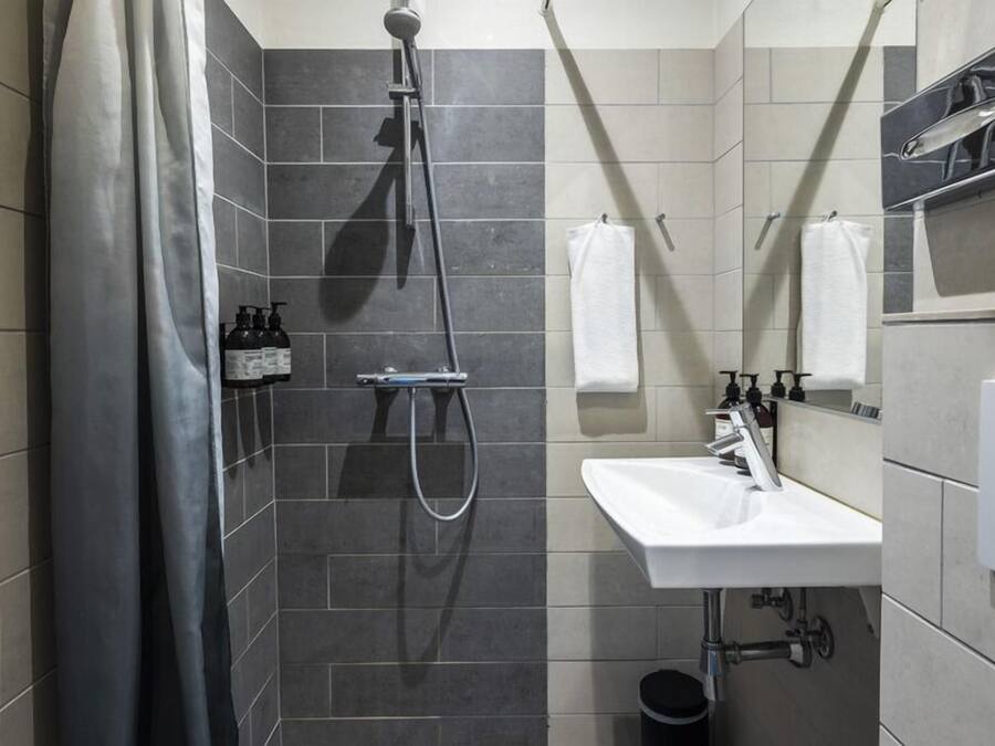 A modern bathroom with a shower, a sink, and a mirror.