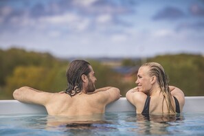 Deux personnes dans un bain à remous, avec un paysage naturel en arrière-plan.