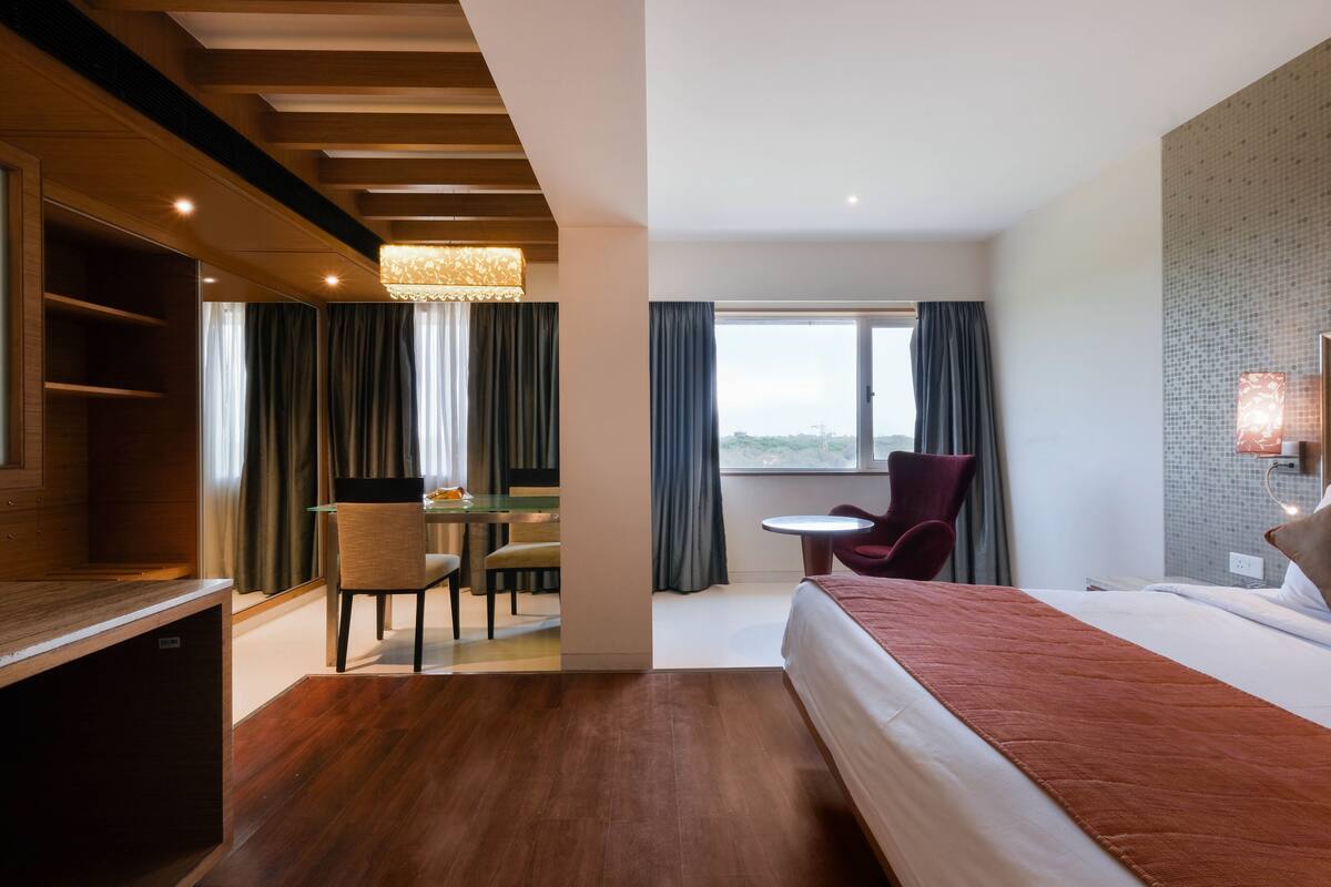 A hotel room with a large bed, a desk, a chair, and a TV.