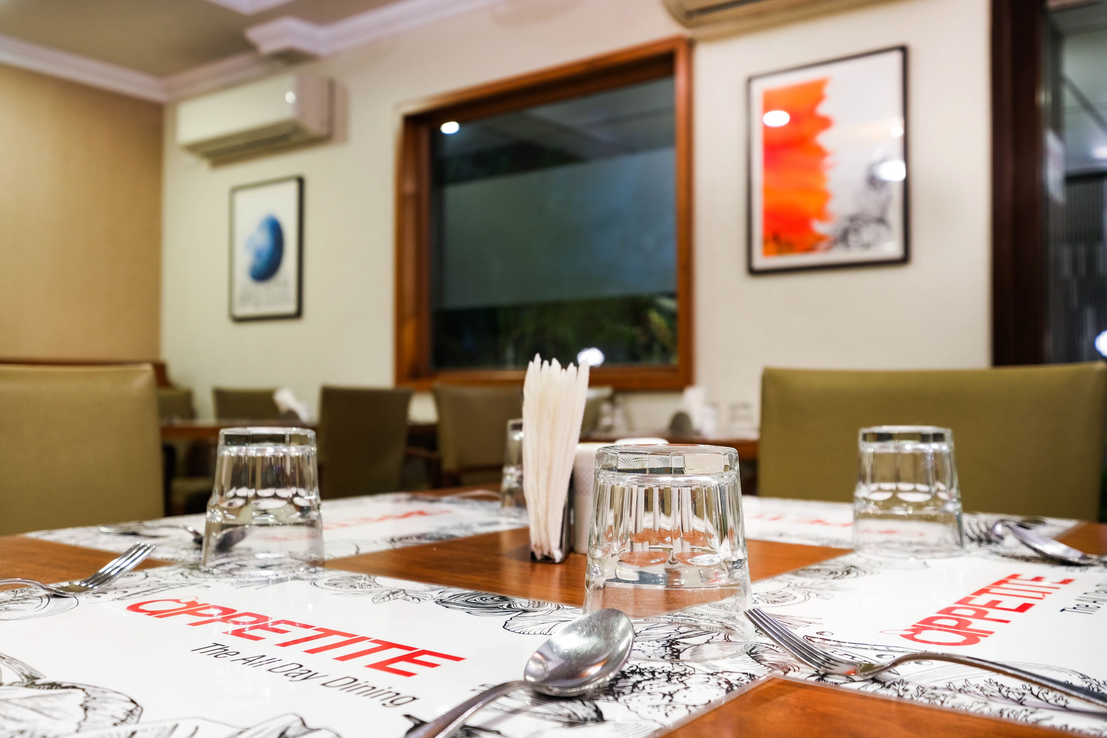 Une table à manger dressée avec des couverts, des verres et un menu intitulé « Cappuccino ».