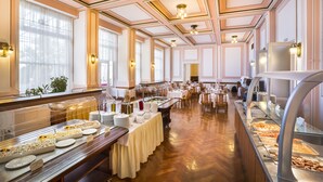 A buffet setup with multiple serving stations, a long table with a white tablecloth, and a ceiling with decorative moldings and lighting fixtures. - Villa Elsa - Liburnia (Lovran)