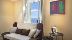 Quarto moderno com sofá, uma mesinha com controle remoto e um copo, e um quadro na parede.