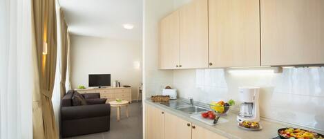 A modern kitchen with wooden cabinets, a built-in stove, and a dining area with a sofa and a small table.