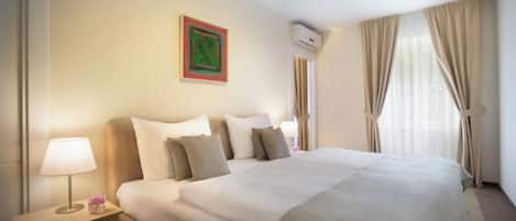 A hotel room with a bed, bedside tables, a lamp, and a window with curtains.