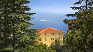 A coastal building with a red-tiled roof, overlooking a calm sea with a yacht. - Apartments Belvedere - Liburnia (Lovran)