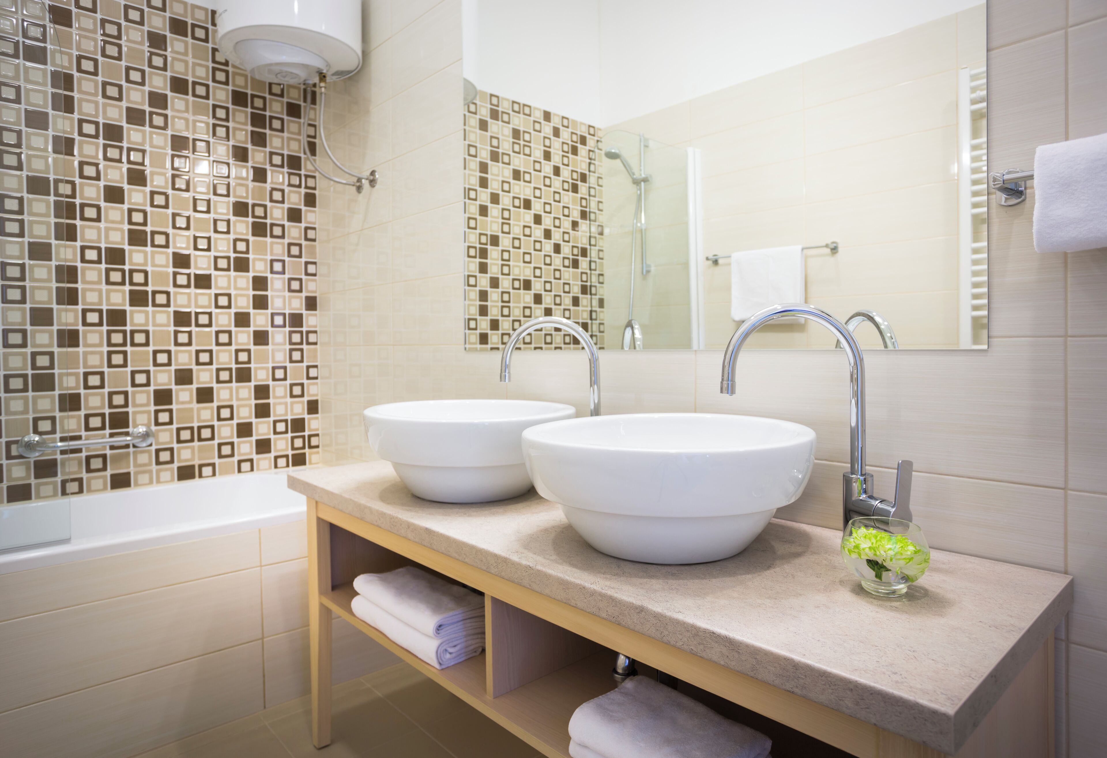 A modern bathroom with two sinks, a shower, and a mirror.