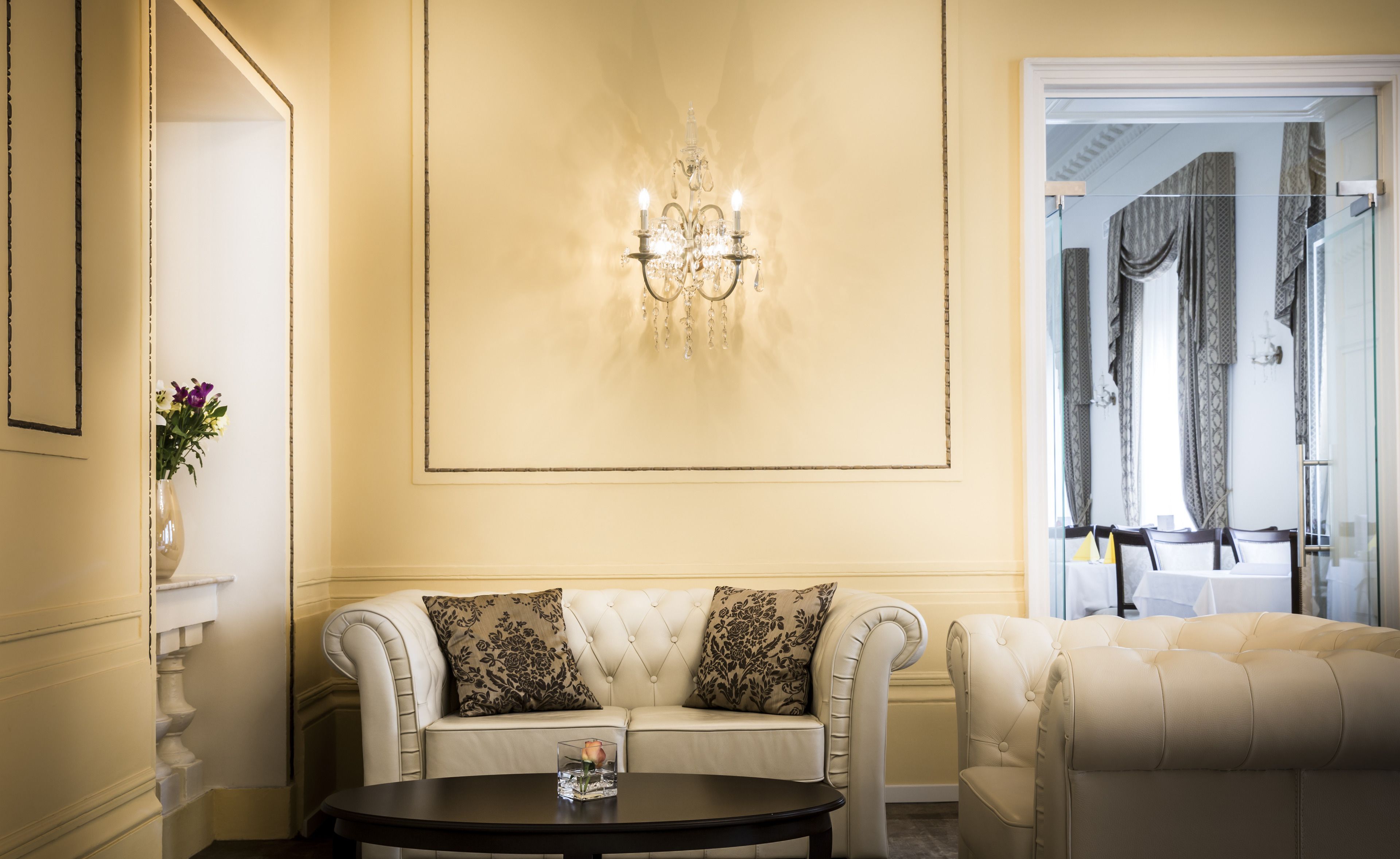 A room with a white sofa, a round table, and a chandelier.