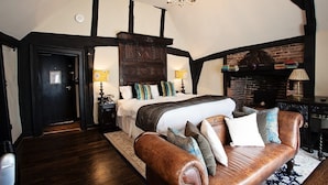 Un dormitorio con una cama grande, un sofá de cuero, una chimenea y un candelabro.