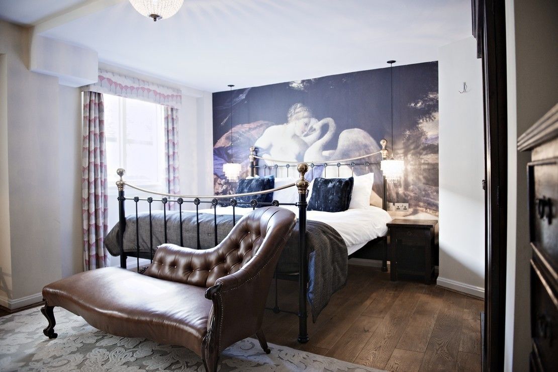 Un dormitorio con cama, una silla, una mesita de noche y un mural en la pared.