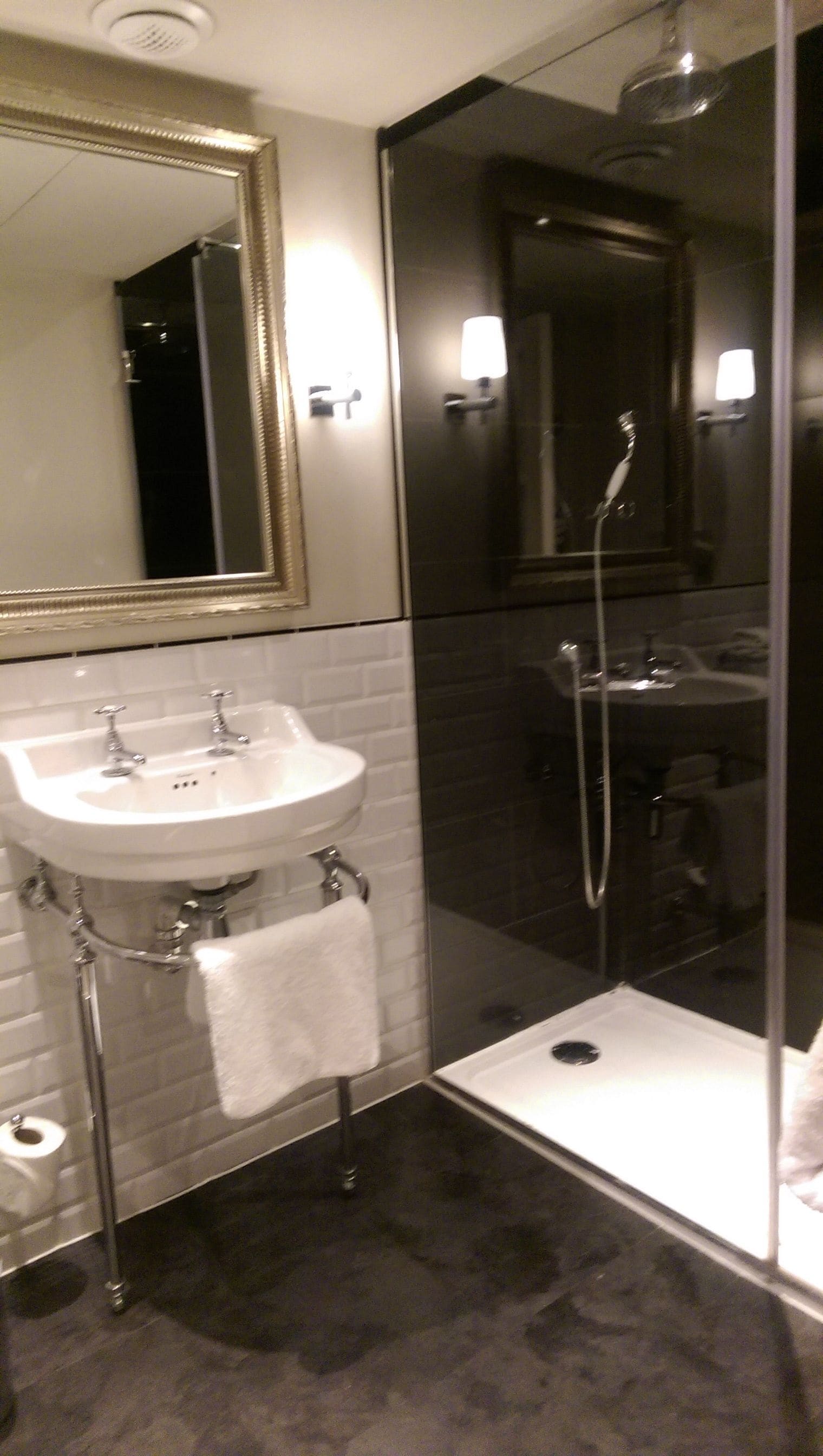 Un baño moderno con un lavamanos blanco, una cabina de ducha de vidrio y un espejo grande.