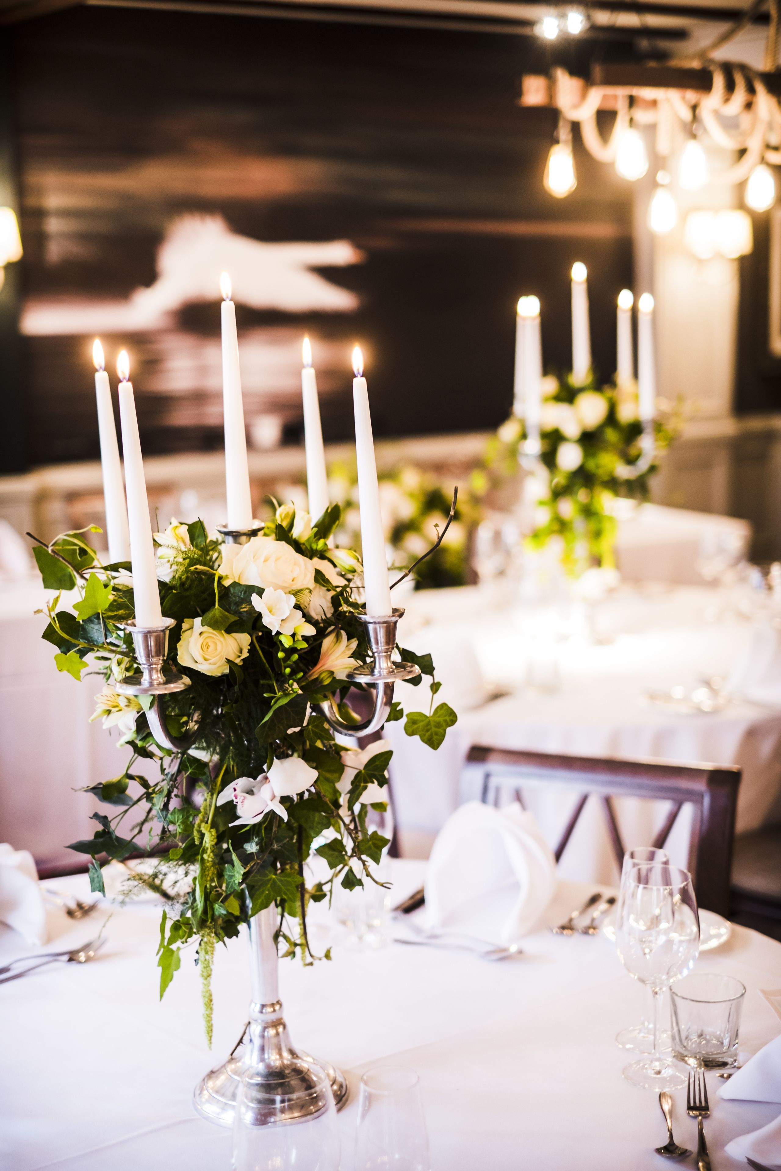 A table set for dining with white tablecloths, candles, and floral centerpieces.