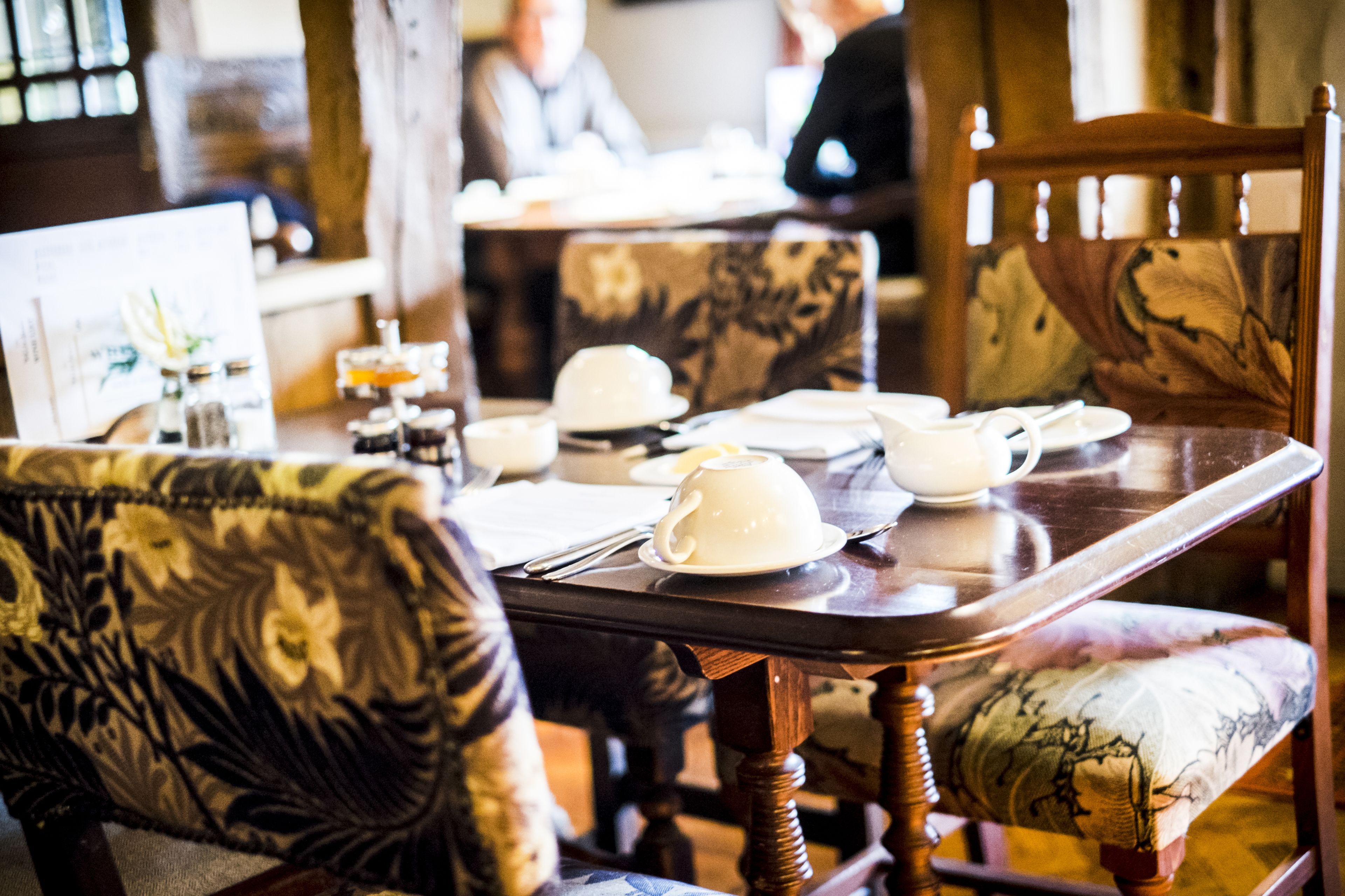 A dining area with wooden furniture, including a table and chairs with floral upholstery.