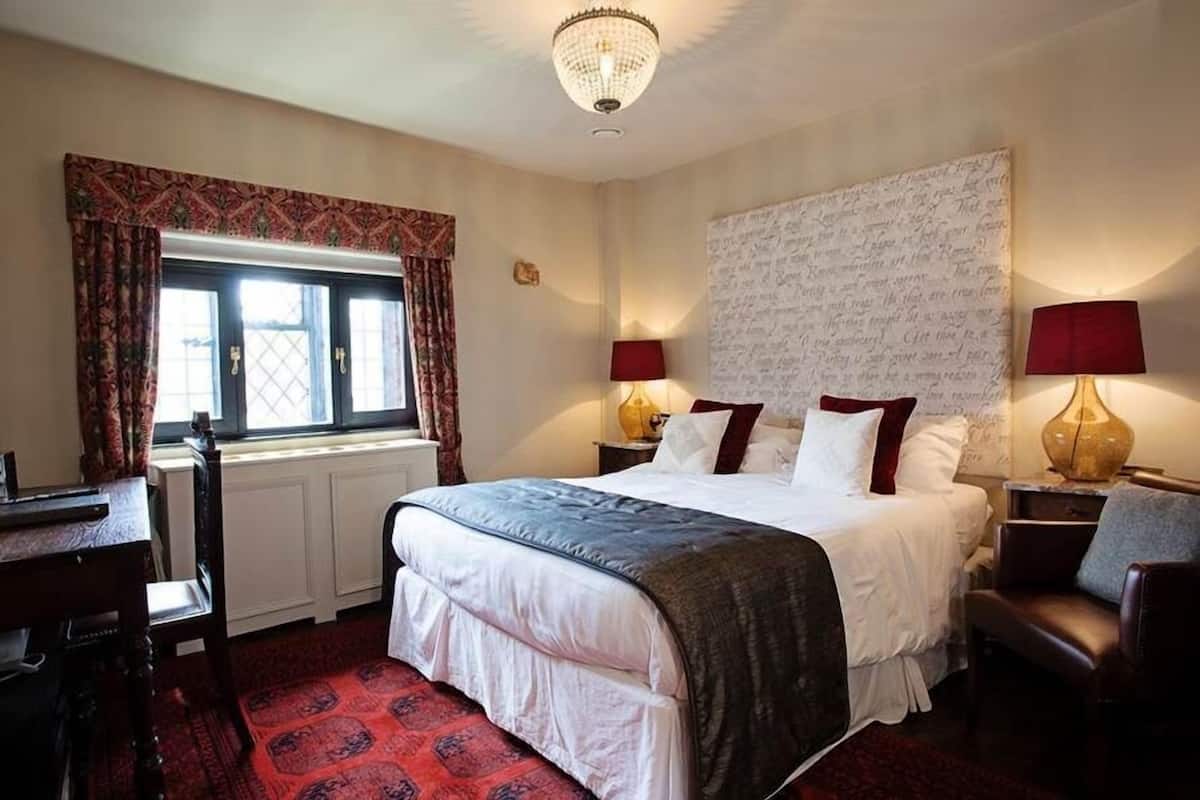 Une chambre d’hôtel avec un grand lit, deux tables de chevet avec des lampes, un bureau et une chaise.