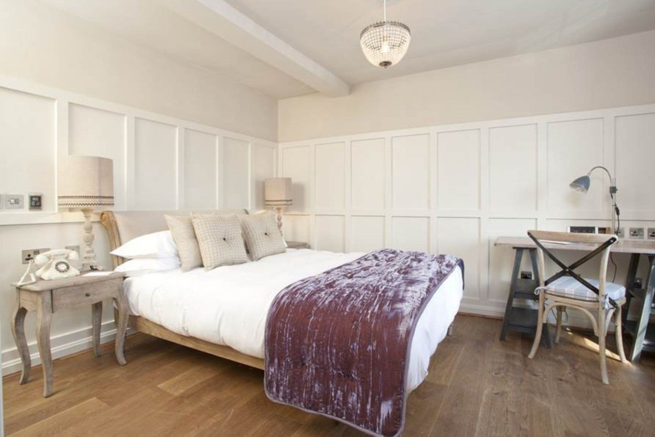 A bedroom with a large bed, bedside tables, a desk, and a chair.