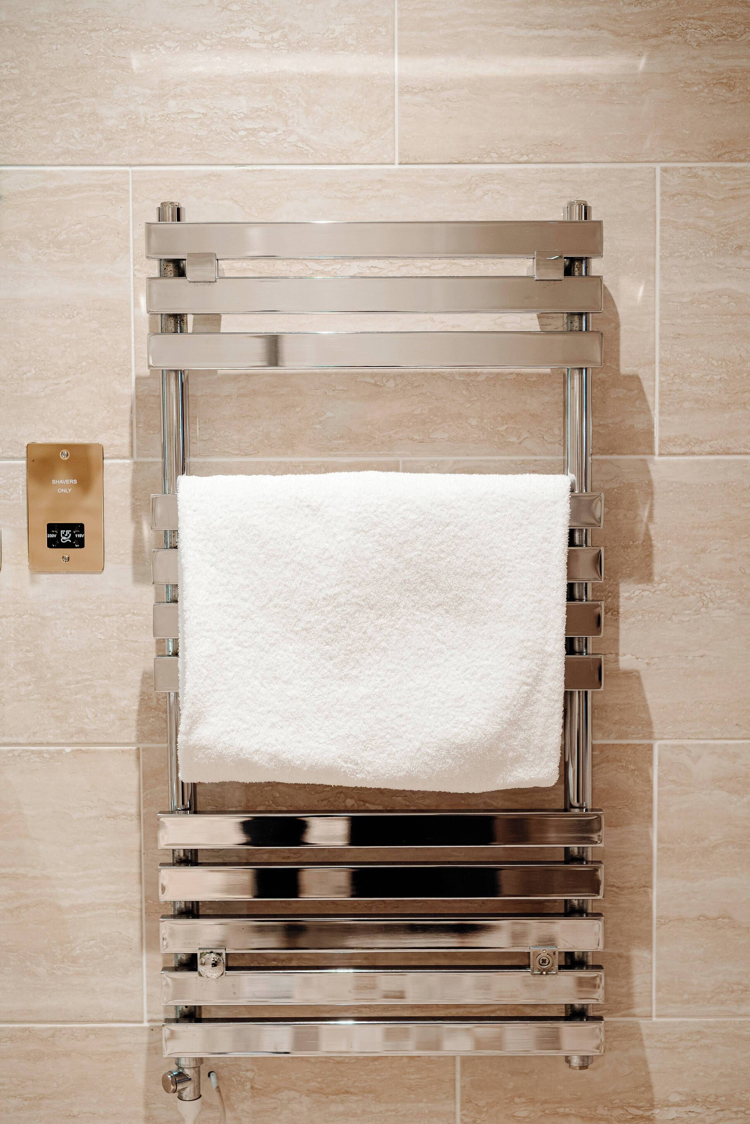 A wall-mounted towel warmer with a white towel hanging on it.