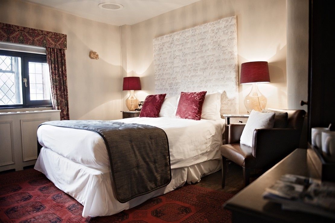 A neatly arranged hotel room with a large bed, two bedside tables with lamps, a chair, and a small table with a lamp.