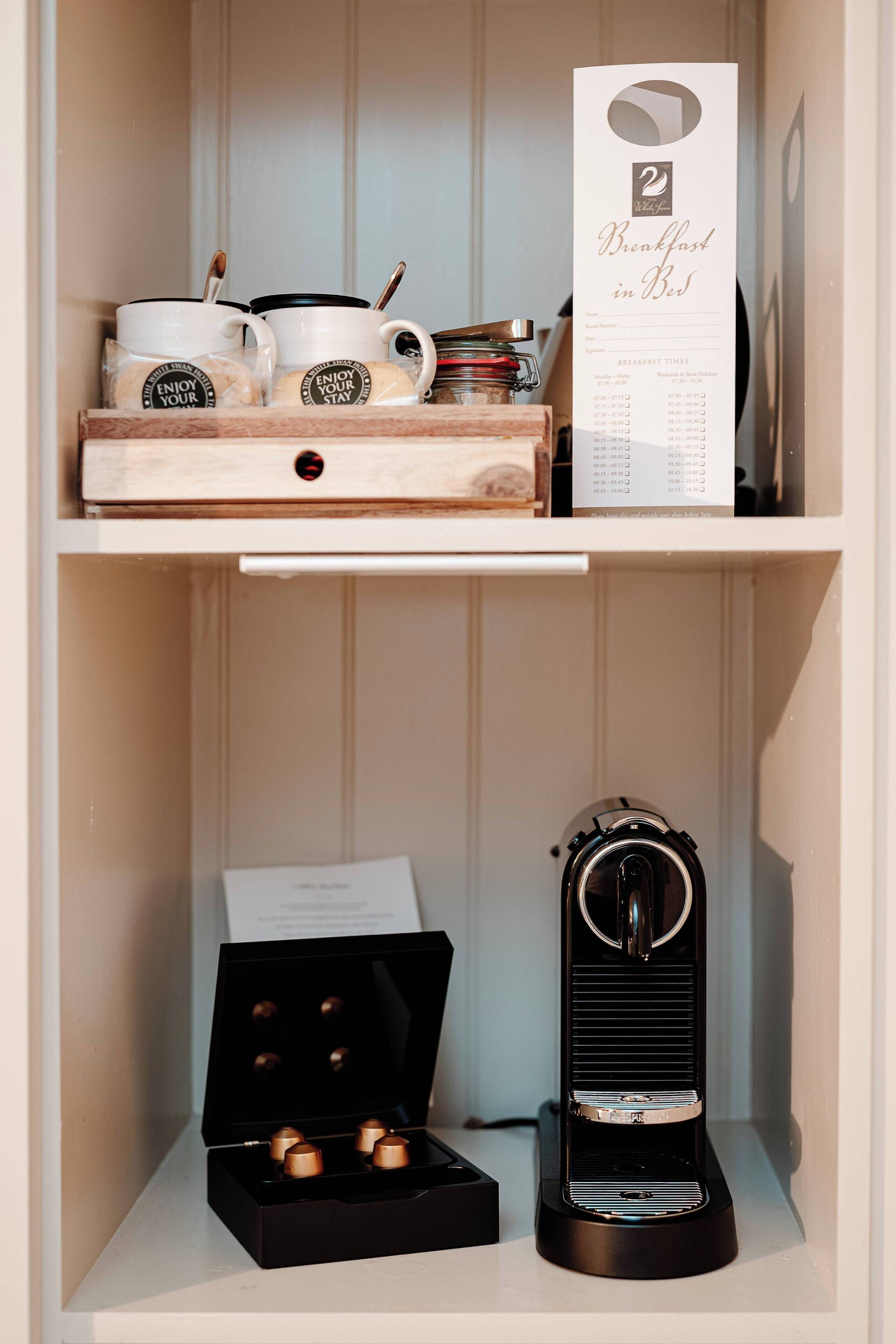 A shelf with a coffee maker, cups, and a menu.