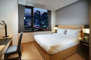 A hotel room with a bed, a desk, a chair, and a view of a cityscape at night. - Fraser Place Namdaemun Seoul (Seoul)
