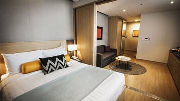 Una habitación de hotel moderna con una cama grande, un escritorio con lámpara, un sofá y una pequeña mesa.
