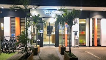 The exterior of Tulip Inn Hotel with a modern design, featuring a prominent entrance, potted plants, and a visible reception area.