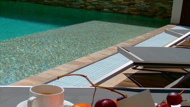 A breakfast setup with croissants, fruit, a glass of orange juice, and a cup of coffee on a table by a poolside. - Tulip Inn Sainte Clotilde La Reunion (Saint-Denis)