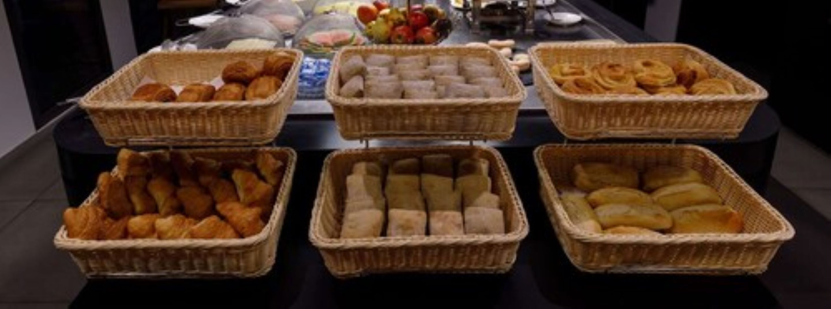 A buffet table with various baked goods in wicker baskets.
