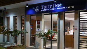 The exterior of Tulip Inn hotel with a modern design, featuring large glass doors and a reception area visible inside. - Tulip Inn Sainte Clotilde La Reunion (Saint-Denis)